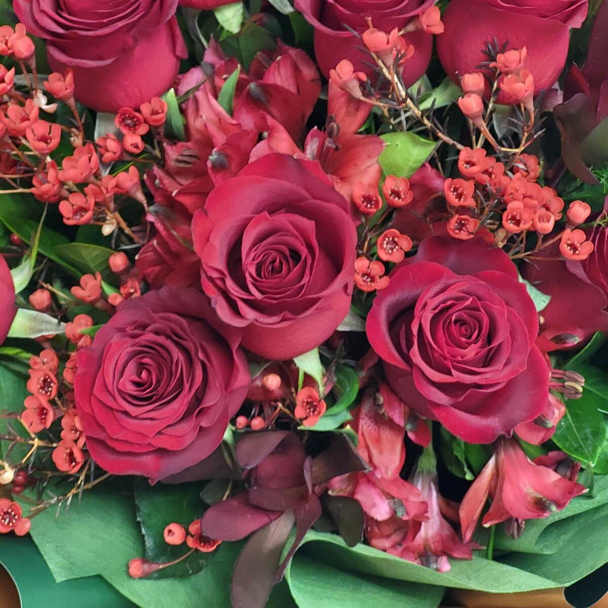 Elegant red roses mixed with red wax flowers and alstroemeria, accented by fresh foliage for a vibrant, full arrangement - 優雅紅玫瑰配紅色蠟花及百合花,綠葉點綴,層次豐富