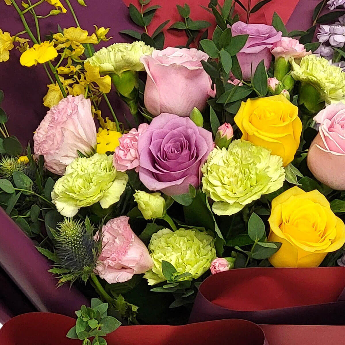Elegant bouquet of pastel roses and green carnations 柔粉、薰衣草、亮黃玫瑰融合清新綠康乃馨,佐以豐富綠葉與深紫紅包裝紙,營造出高雅與春日氣息並存的視覺饗宴。