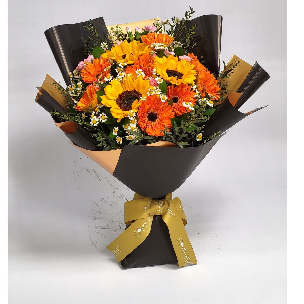 Mixed bouquet of sunflowers, bright orange gerberas, chamomile, and assorted greenery wrapped in black and gold paper. 向日葵、橙色太陽菊、洋甘菊及綠葉混合花束,配黑金包裝紙及金色絲帶。