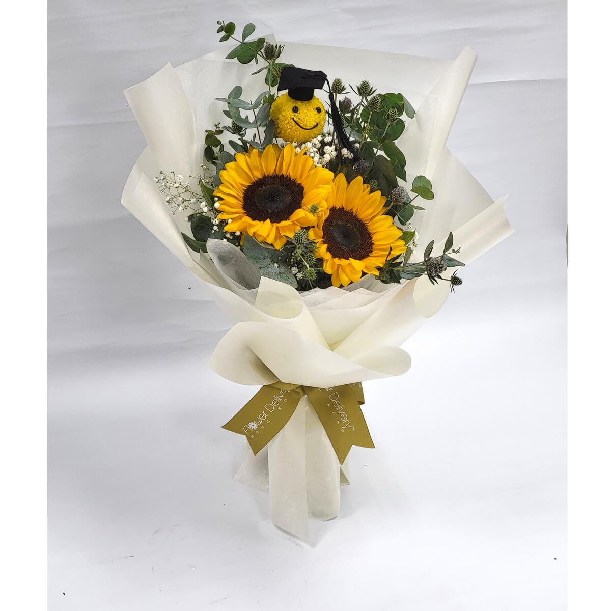 Bouquet of two sunflowers, eucalyptus, baby’s breath, and a yellow smiley pompom flower with a cap, wrapped in white paper. 向日葵花束配尤加利葉、滿天星及笑臉乒乓菊,白色包裝。