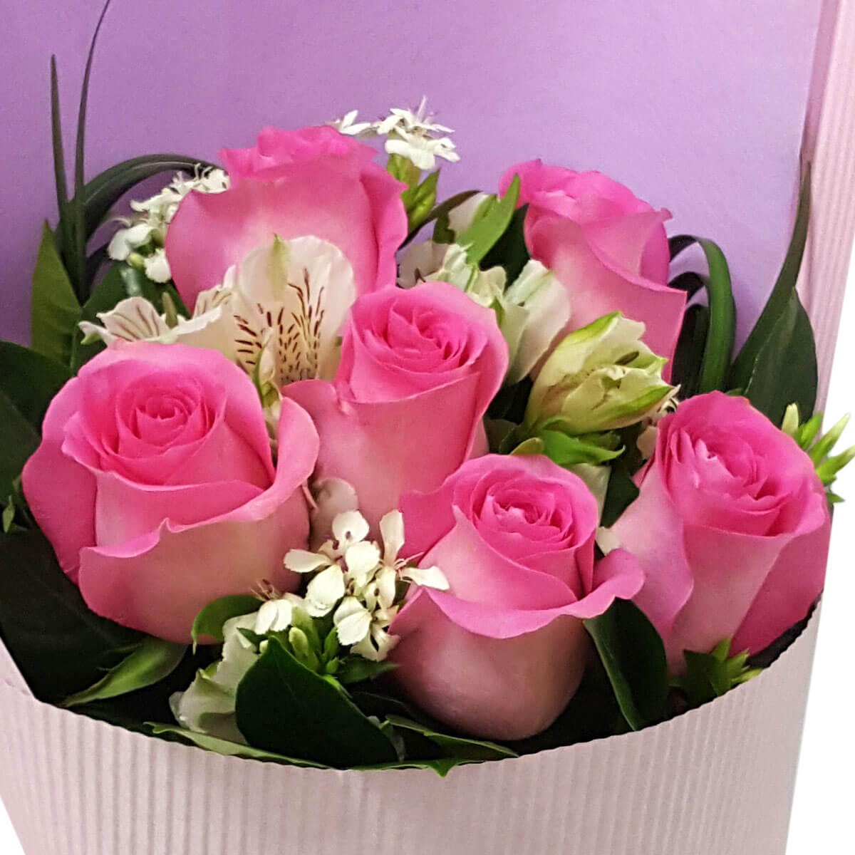 Romantic bouquet of pink roses and white accent flowers nestled in lush greenery with lavender wrapping. 粉紅玫瑰與白色配花交織,綠葉襯托,展現浪漫氣息。