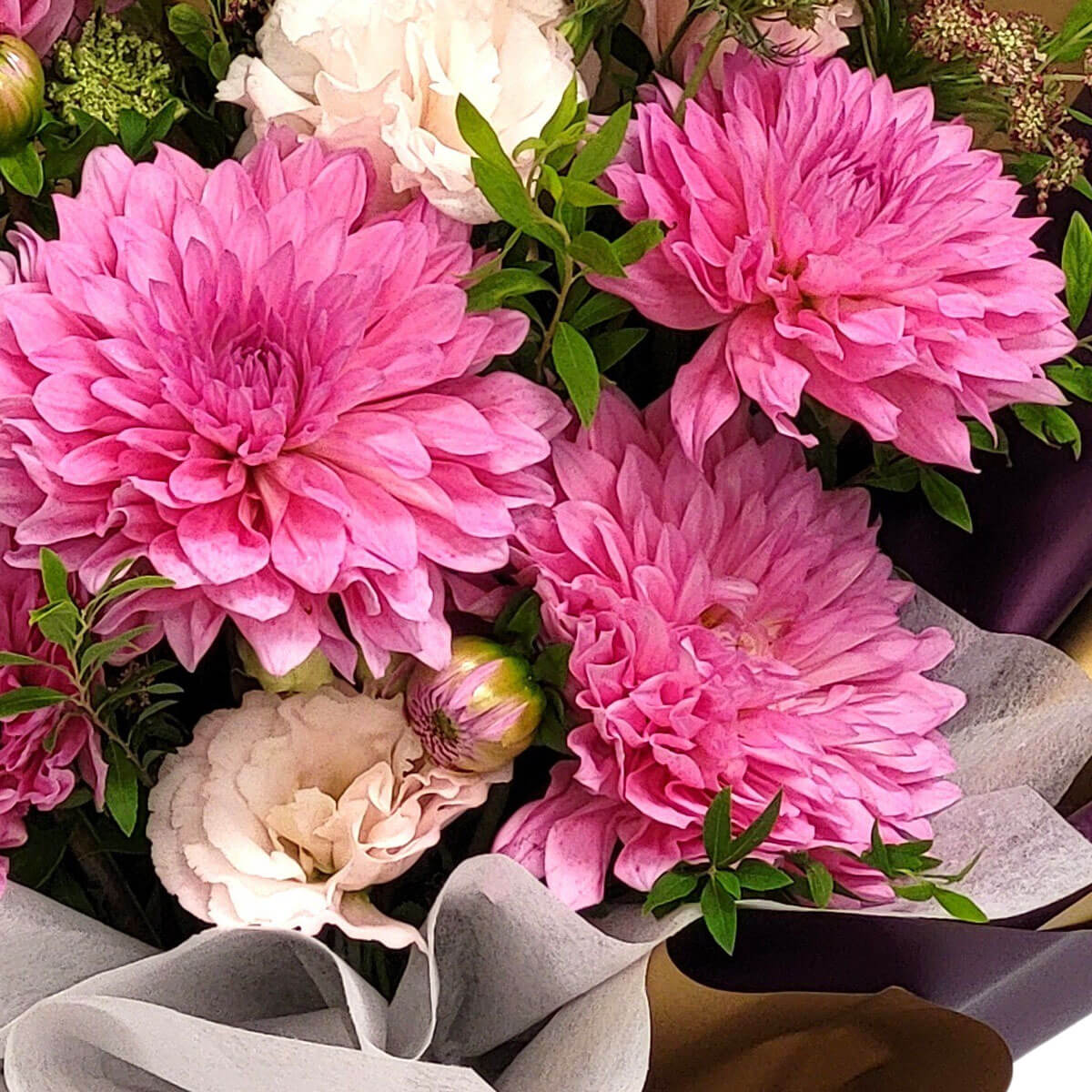 Bold pink dahlias and creamy lisianthus form a lush bouquet 粉紅大理花熱烈盛開,與奶白洋桔梗共譜花語,綠葉點綴其中,展現自然雅致的氛圍。