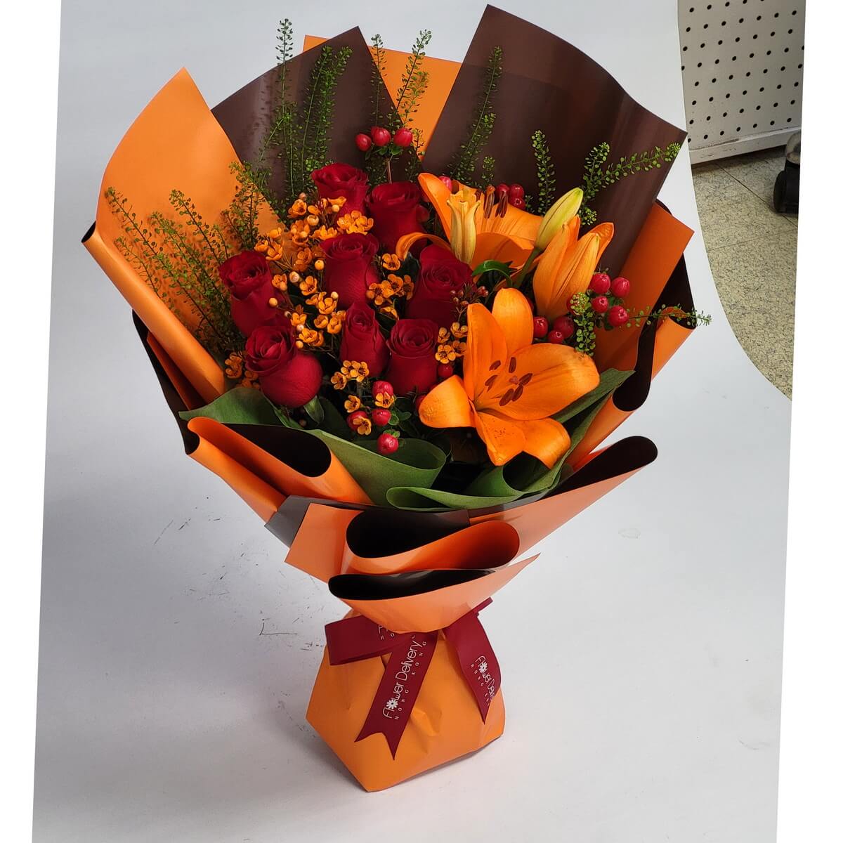 Full bouquet with red roses, vibrant orange lilies, yellow wax flowers, and red hypericum berries, wrapped in layered orange and brown paper - 紅玫瑰、橙百合、黃蠟花及紅朱頂果花束,橙啡雙層包裝