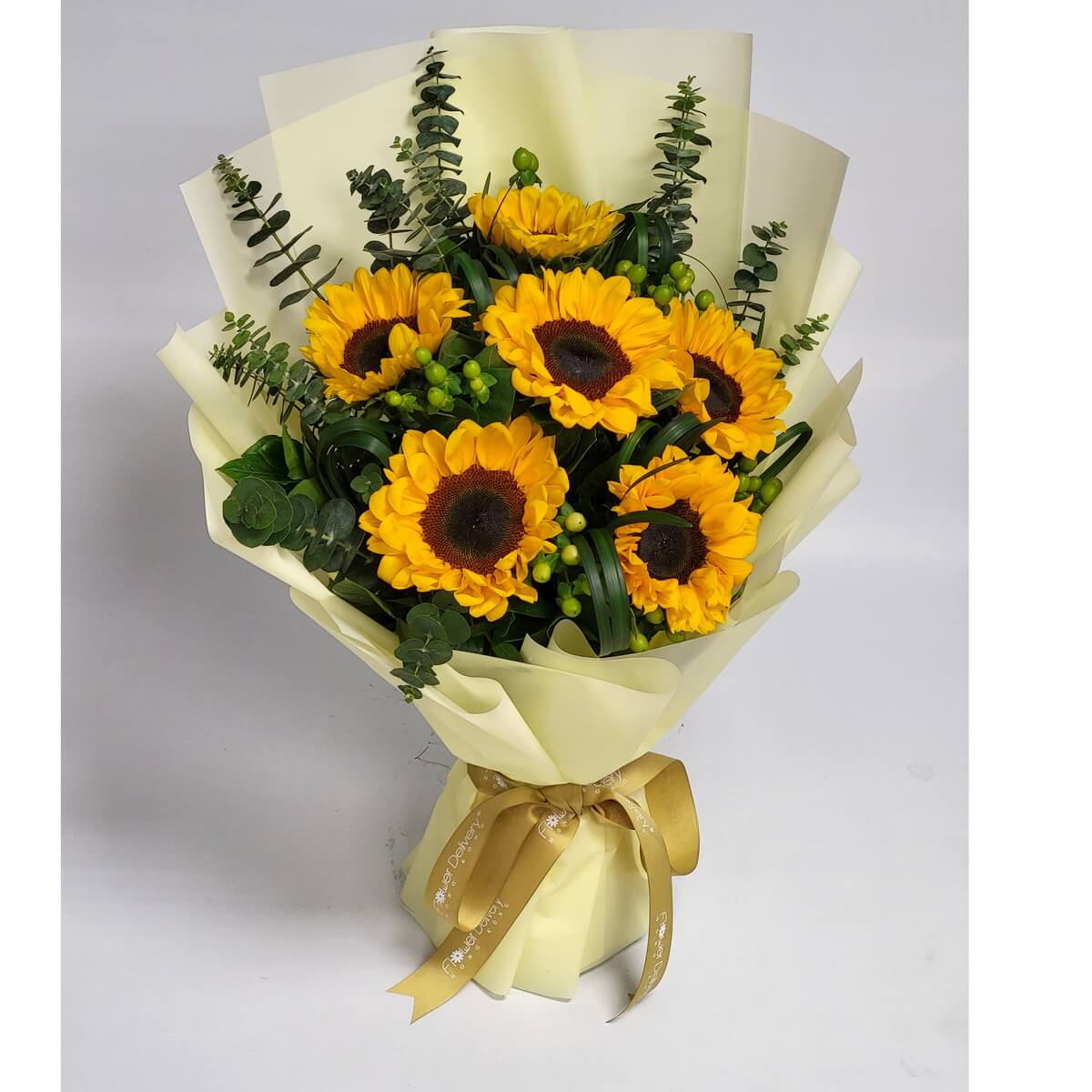 Full bouquet featuring six sunflowers, green hypericum berries, spiral foliage, and eucalyptus, elegantly wrapped in pale yellow paper with gold ribbon - 六朵向日葵配綠朱頂果、螺旋葉及尤加利葉,淡黃金絲帶包裝花束