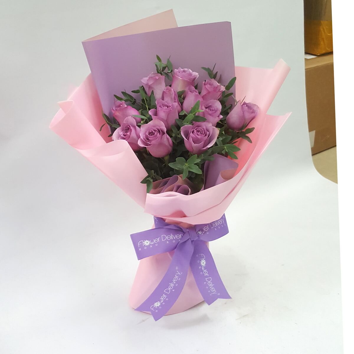 A charming bouquet of lavender roses arranged with leafy greenery, wrapped in soft pink and purple pastel paper, and tied with a lavender ribbon. 清新淡紫玫瑰,浪漫柔和,適合表達溫柔的愛意與感激。