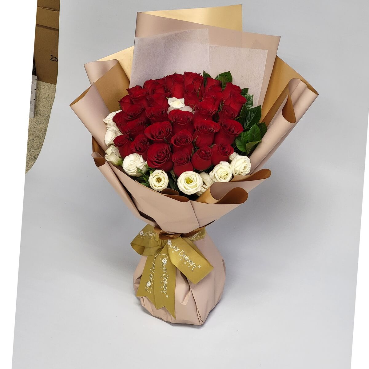 Lush bouquet of deep red roses encircled by creamy white roses, wrapped in champagne and gold-toned paper with a gold ribbon. 紅白玫瑰交織,香檳金包裝高貴典雅,傳遞濃濃愛意與莊重心意。