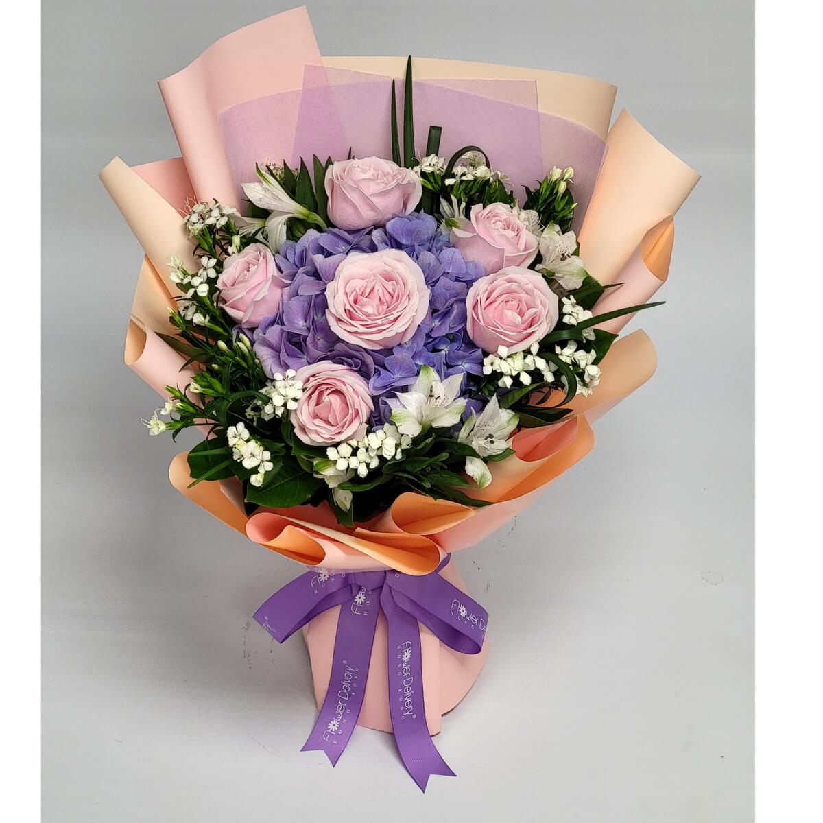 Elegant bouquet with pink roses, lavender-purple hydrangeas, white alstroemeria, small white filler blooms, and assorted greenery in peach wrapping 粉紅玫瑰、薰衣草紫陽花、白六出花、白配花與混合綠葉包裝於蜜桃色紙中的優雅花束