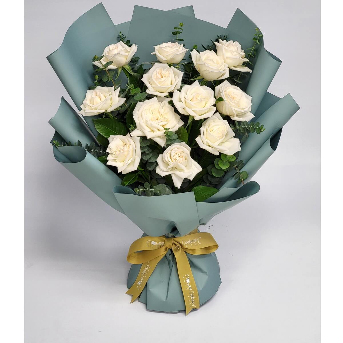 Classic white roses arranged with eucalyptus in sleek sage green wrapping, finished with a golden ribbon. 純白玫瑰與尤加利葉點綴其中,搭配綠松色包裝與金色絲帶,展現高雅與純淨之美。