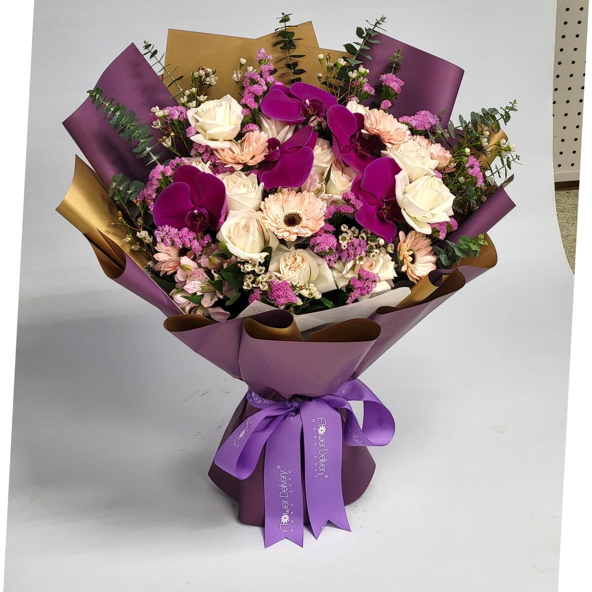 Elegant bouquet in purple wrap featuring fuchsia orchids, cream roses, peach gerberas, pink statice, white waxflowers, and mixed greenery 紫色包裝花束含紫紅蝴蝶蘭、奶白玫瑰、蜜桃非洲菊、粉色勿忘我、白蠟花與混合綠葉