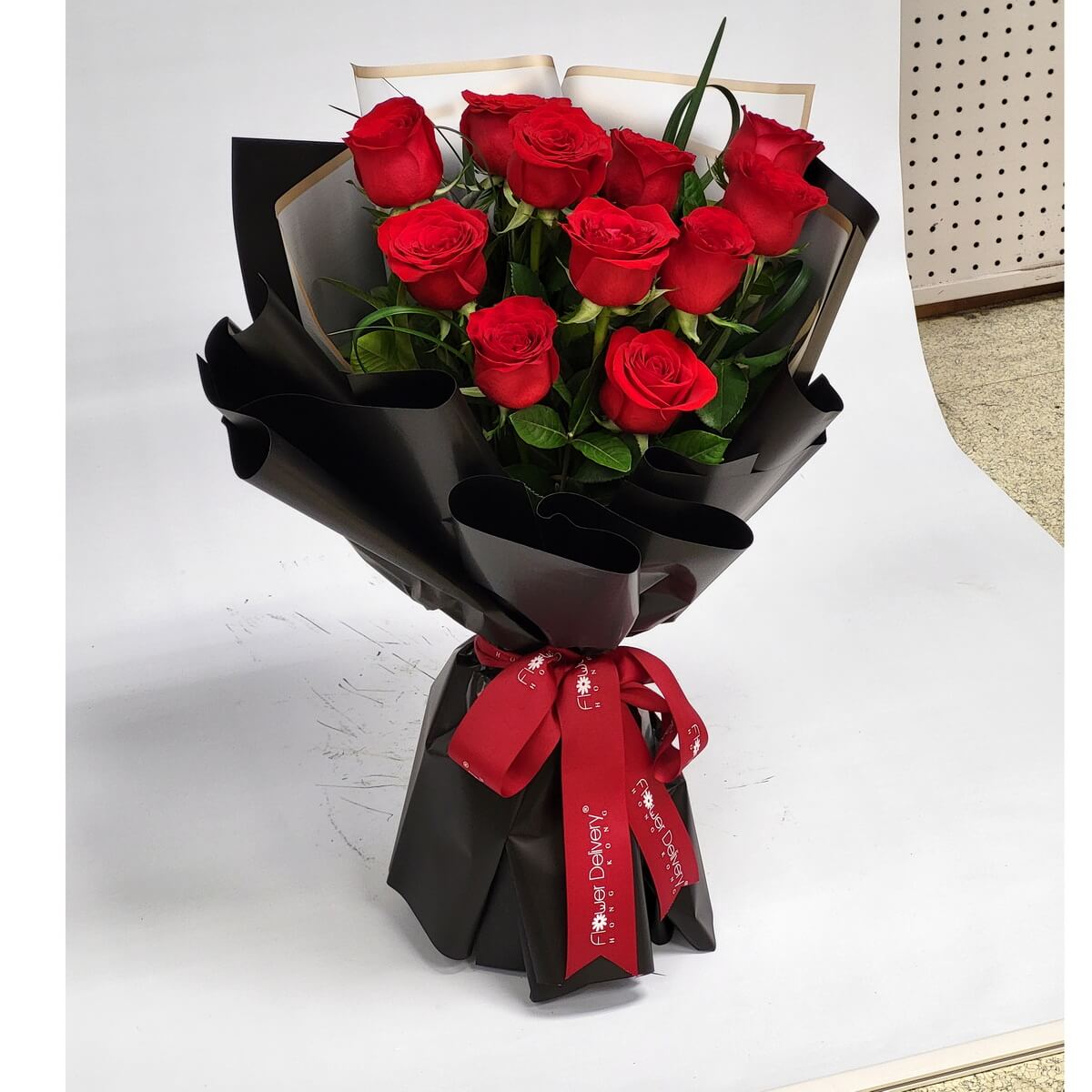 A striking bouquet of red roses wrapped in sleek black paper with a bold red ribbon. Mysterious and passionate. 黑色包裝襯托紅玫瑰的熱烈情感,搭配鮮紅絲帶,低調中散發魅力。