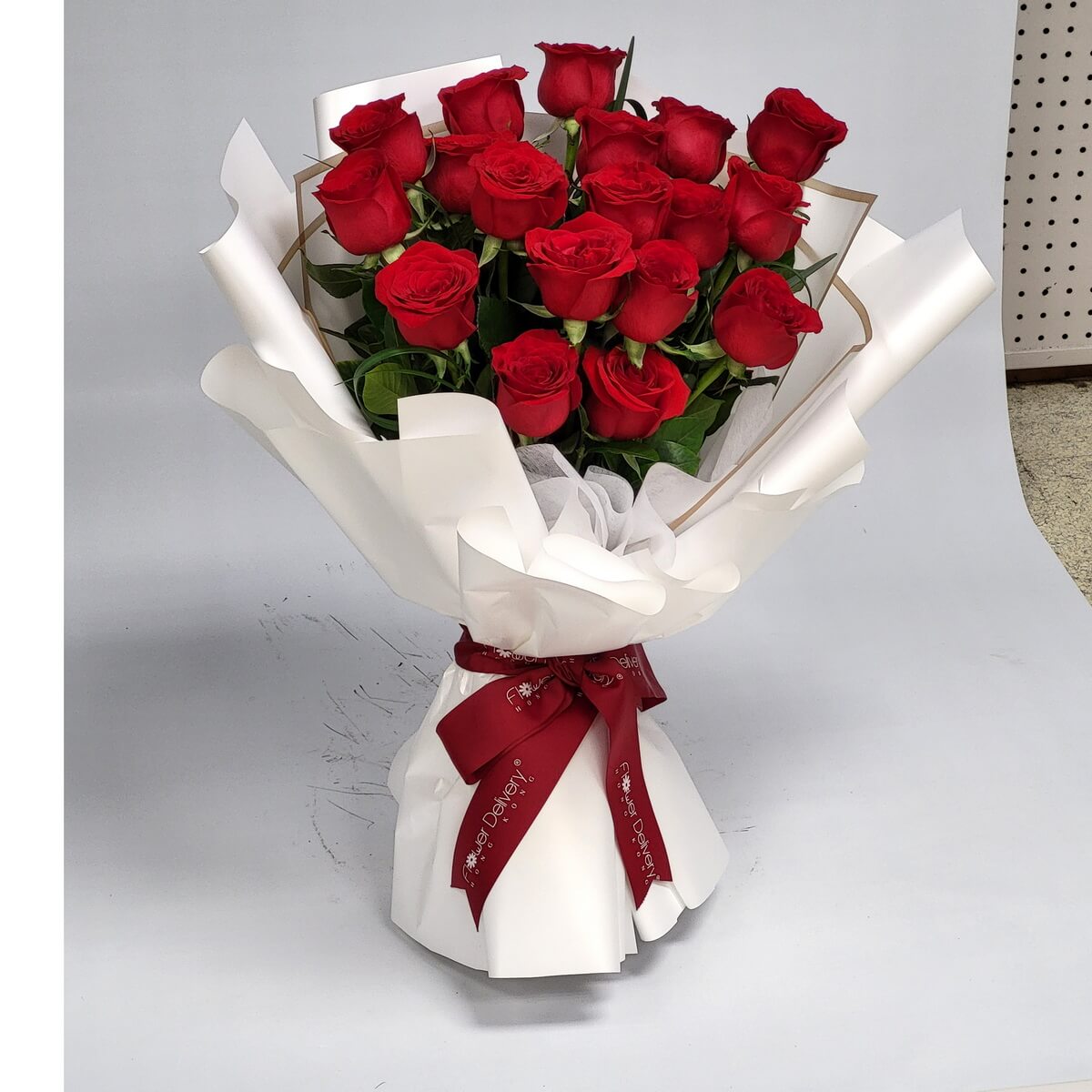 A timeless bouquet of velvety red roses wrapped in elegant white paper and tied with a deep red ribbon. Passionate and refined. 一束紅玫瑰,潔白包裝與酒紅絲帶點綴,盡顯愛意與優雅。