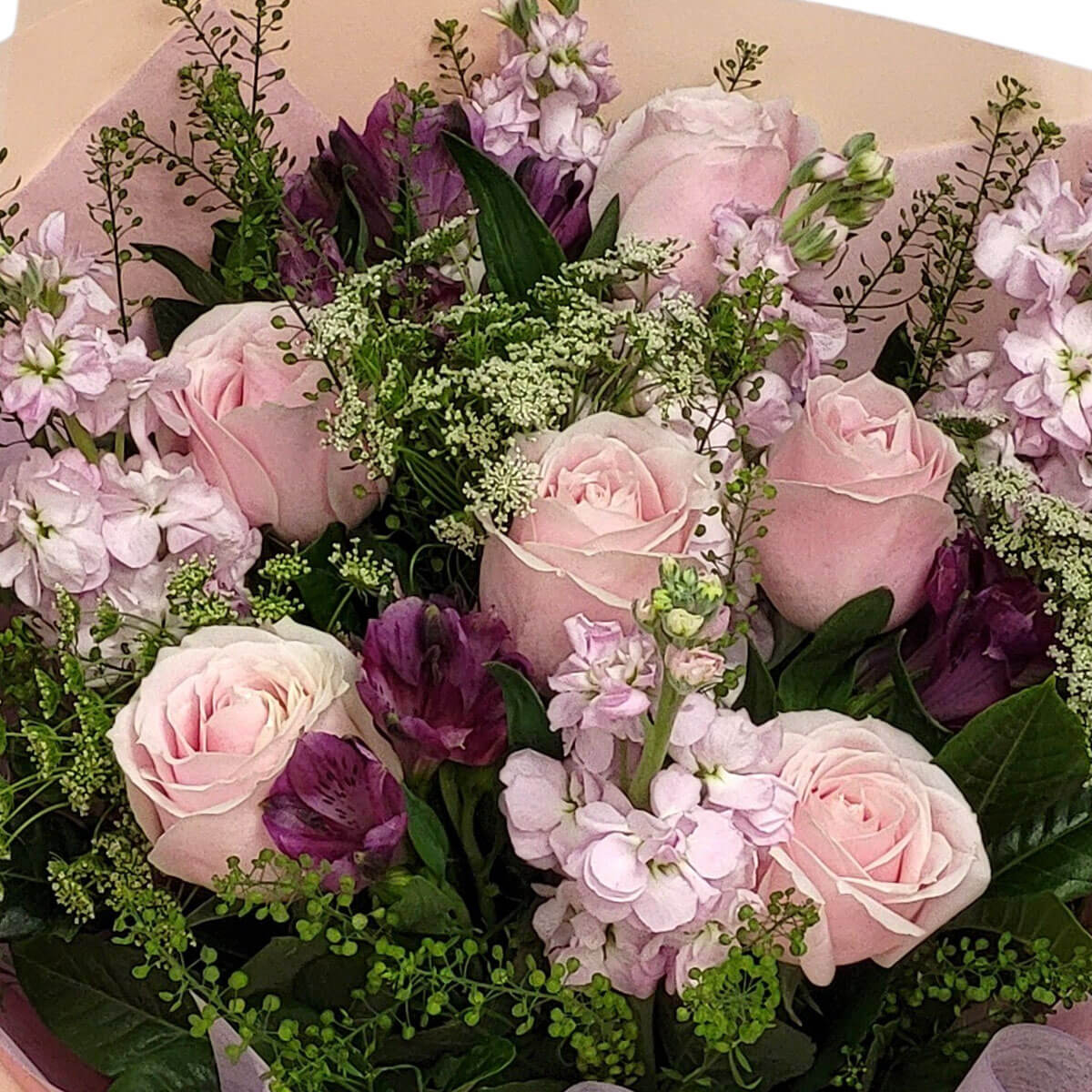 A lush mix of blush roses, mauve alstroemeria, and delicate greens evokes a wild garden charm 粉玫瑰與紫百合花交織綠葉,如同微風拂過的花園,洋溢自然與優雅。