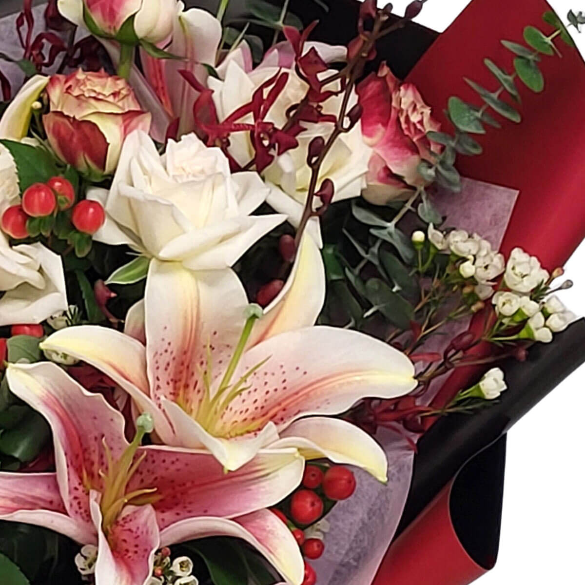This rich bouquet blends pink lilies, creamy roses, red orchids, and berries for dramatic flair 粉色百合、奶白玫瑰與紅色蘭花果實交融,展現熱情與高貴。