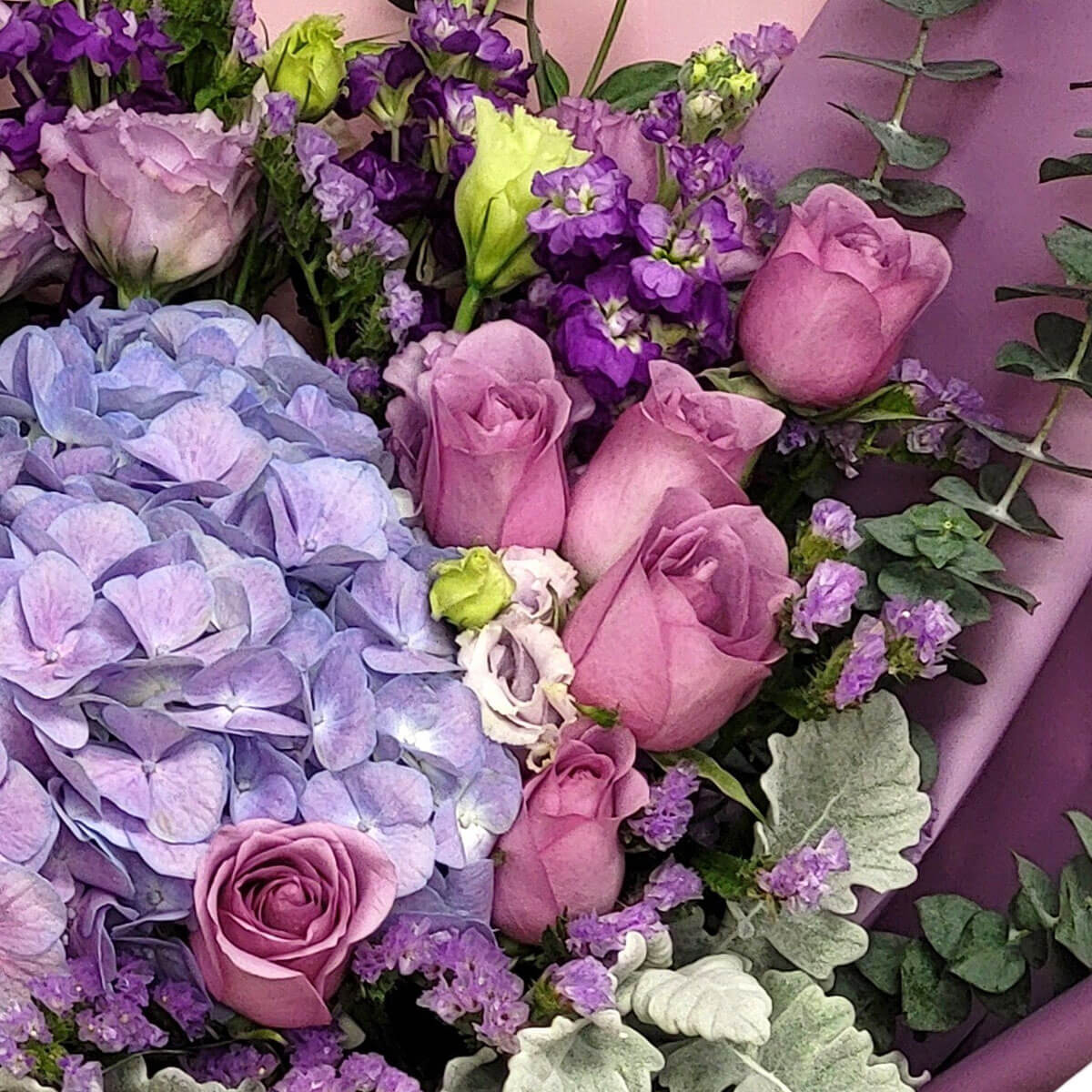A romantic bouquet with lavender hydrangeas, mauve roses, lisianthus, and textured greenery 淡紫繡球、藕紫玫瑰與桔梗交織而成,配以葉材與紫花點綴,浪漫又細緻。