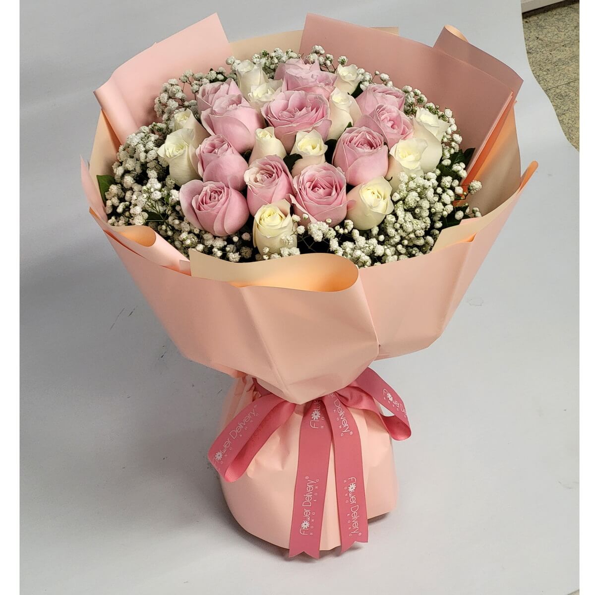 Bouquet of alternating pink and white roses framed by baby’s breath, wrapped in soft peach with pink ribbon – 粉白玫瑰交錯排列,滿天星圍繞,蜜桃色包裝與粉紅絲帶點綴