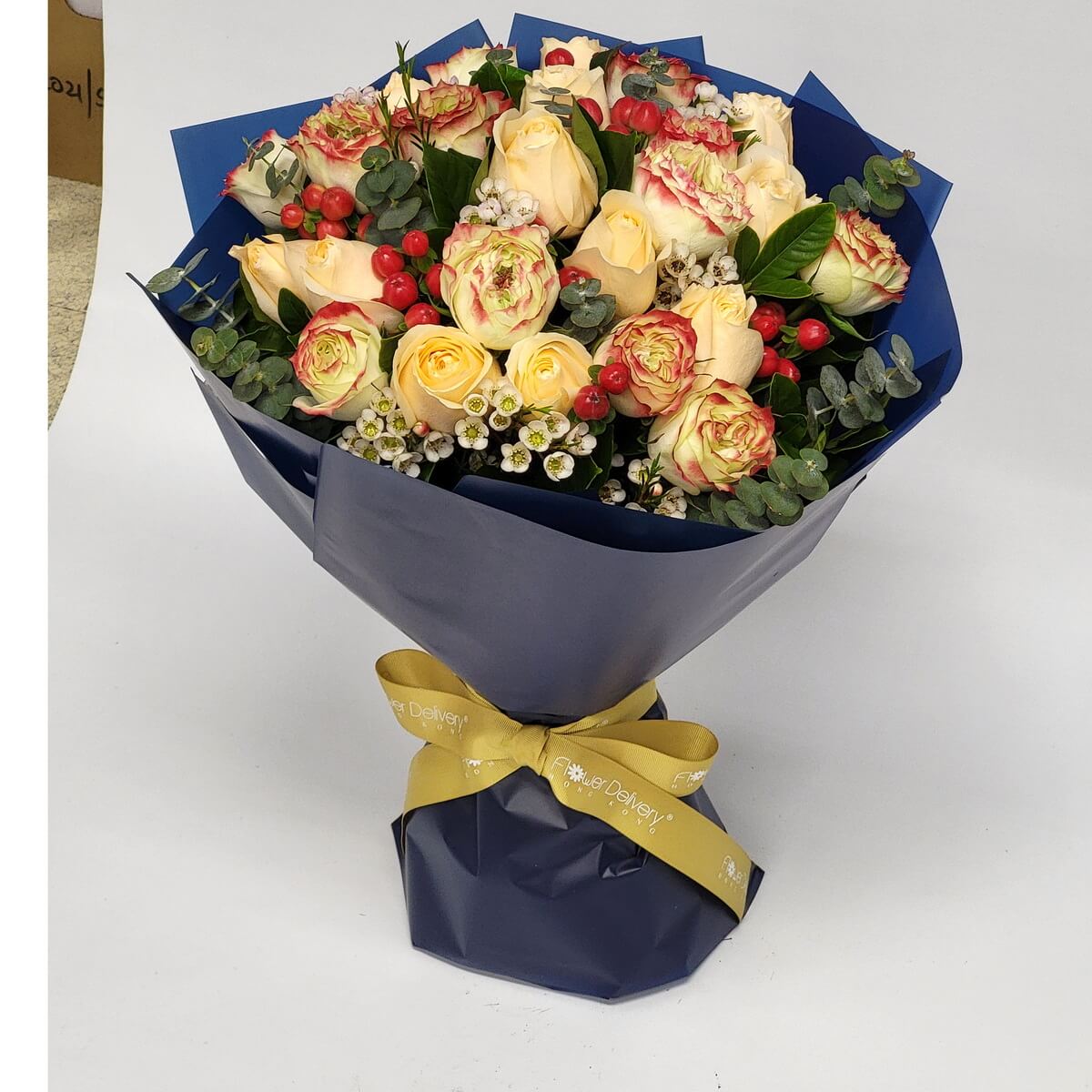 Champagne and bicolor roses with red berries and wax flowers, wrapped in deep navy blue and tied with a golden ribbon. 香檳雙色玫瑰搭配紅果與小白花,深藍包裝與金緞帶,高雅又喜氣。