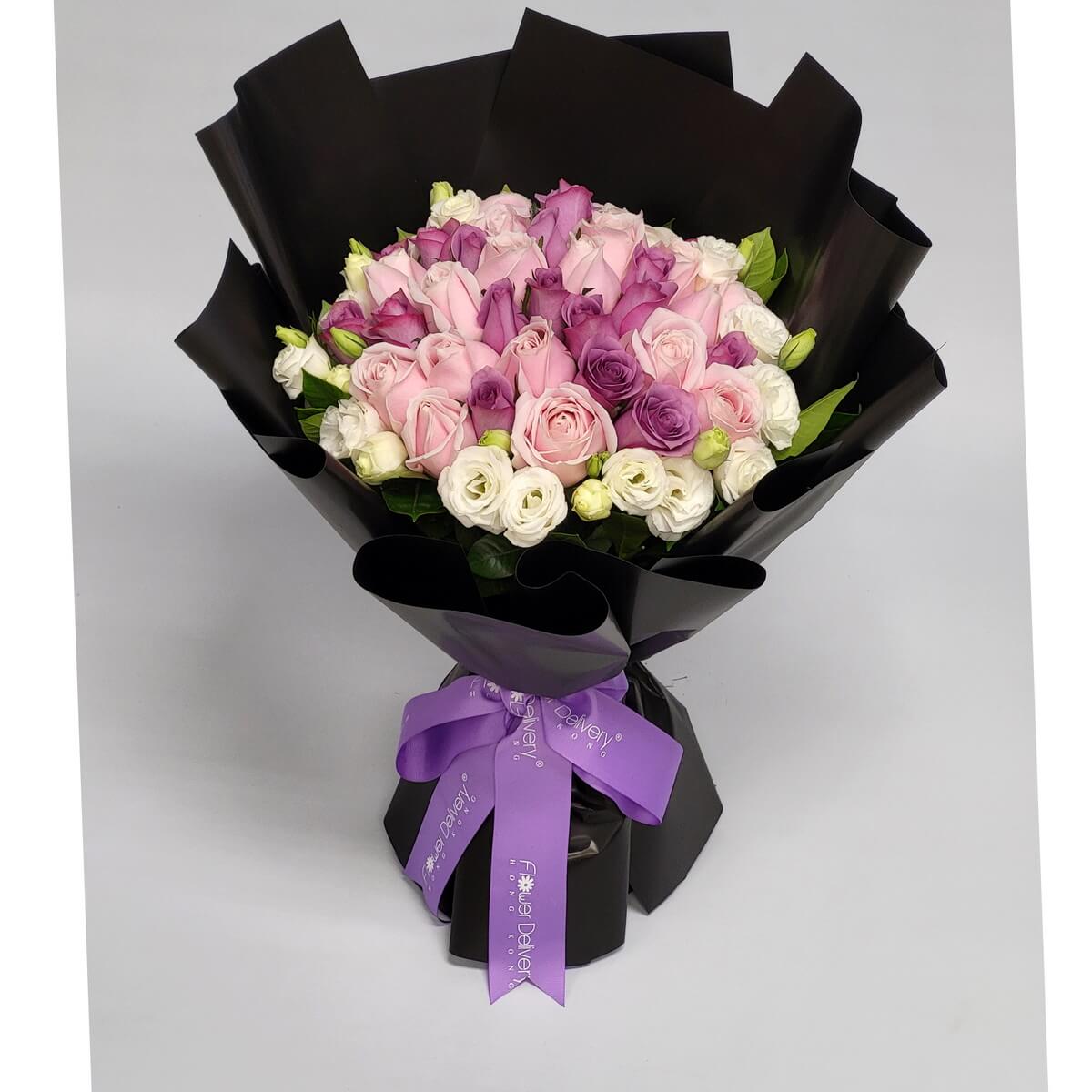Elegant bouquet of pale pink, lavender, and ivory roses, wrapped in sleek black paper with a purple ribbon. 典雅的黑色包裝襯托粉紅、淡紫與奶白玫瑰,展現高貴氣質。