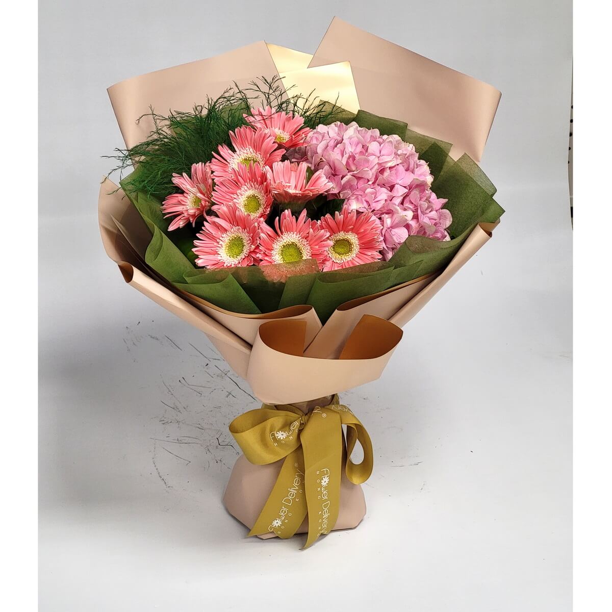 Charming bouquet of pink gerberas and hydrangeas, wrapped in soft taupe and green paper with a golden olive ribbon. 粉紅太陽菊與繡球花花束,配米啡與綠色包裝,金橄欖絲帶點綴,清新迷人。