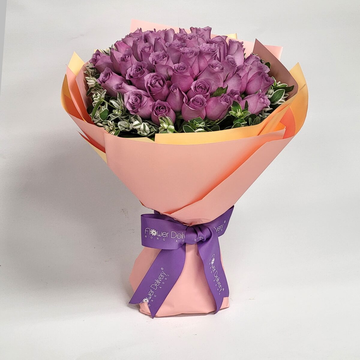 Elegant bouquet of lavender roses accented with soft greenery, wrapped in peach and orange-toned paper and tied with a purple ribbon. 典雅紫玫瑰花束,配搭淡橘色包裝與紫色絲帶,展現高貴氣質。