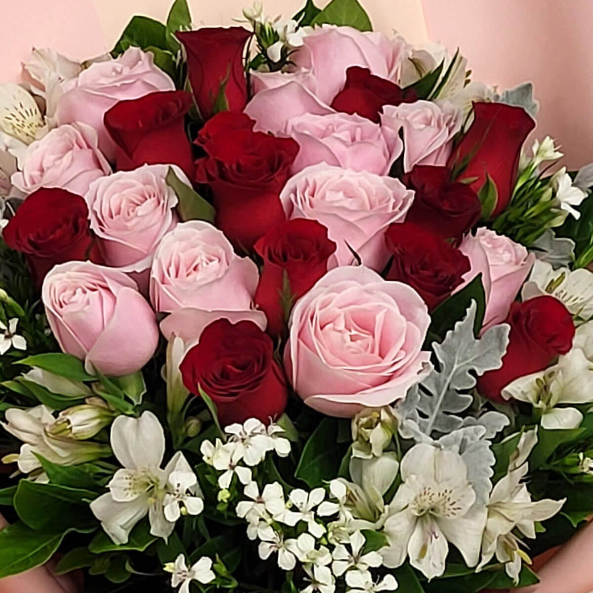 A romantic arrangement of soft pink and deep red roses, accented with delicate white flowers and lush greenery 柔粉與深紅玫瑰交錯,點綴白花與綠葉,展現優雅情懷。