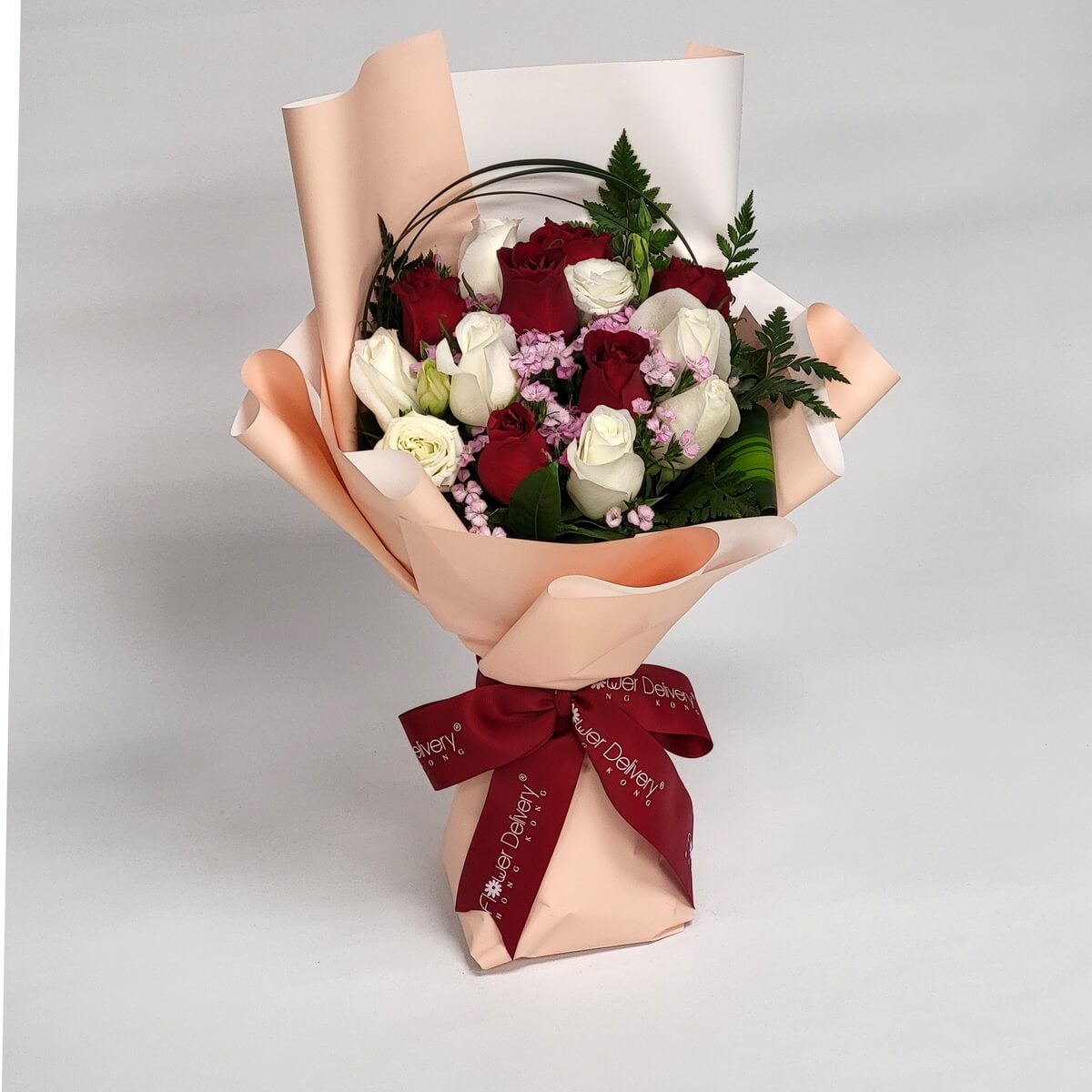 Chic bouquet with red and white roses, pink accents, wrapped in champagne-toned paper with a burgundy ribbon. Romantic with a modern touch. 紅白玫瑰混搭粉色小花,香檳包裝配酒紅絲帶,浪漫中帶時尚。
