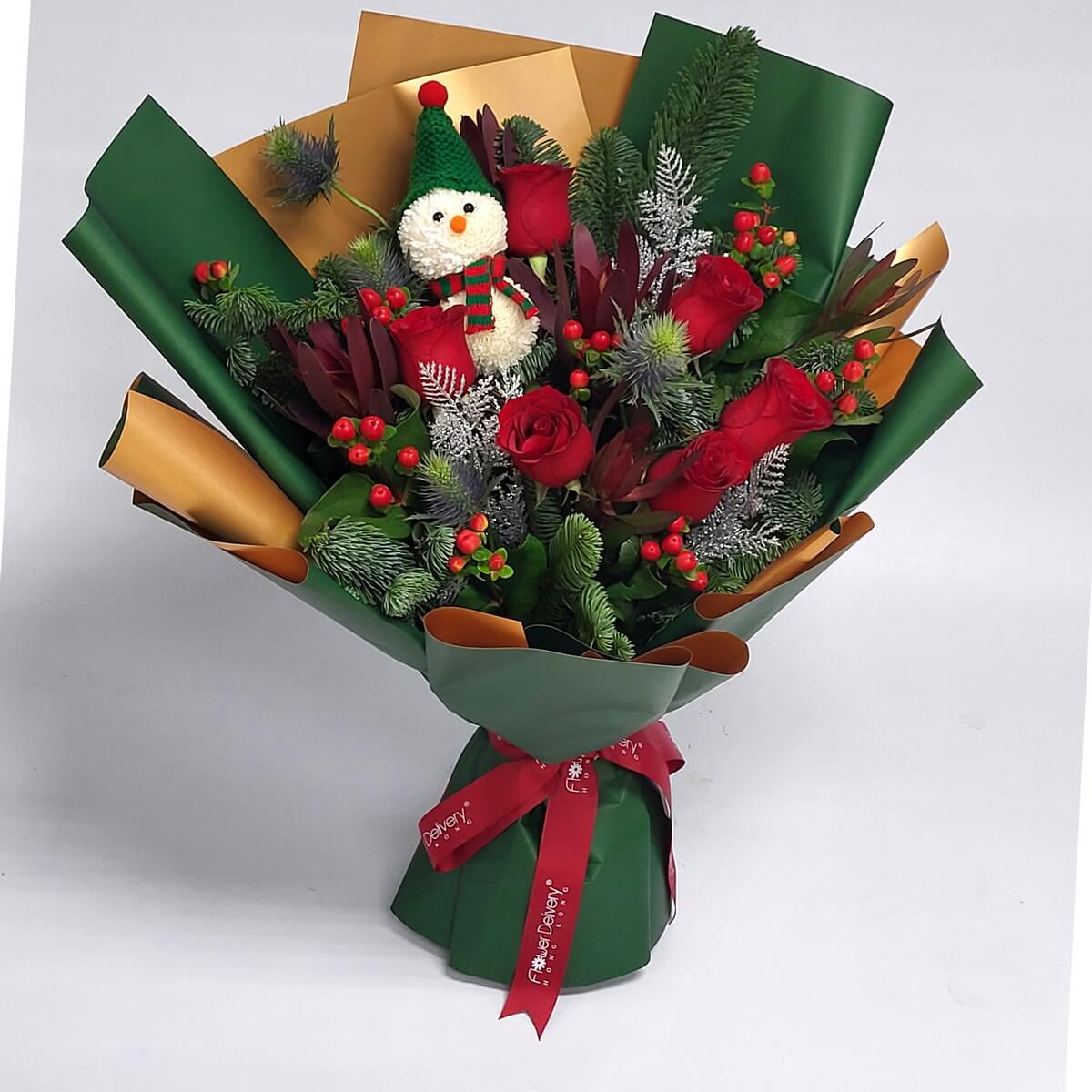 Original view of festive bouquet with red roses, blue eryngium, pine greenery, red hypericum berries, frosted silver foliage, and a snowman crafted from white button chrysanthemums - 節日花束全貌,配紅玫瑰、藍刺芹、松葉、紅繡球果、銀色葉材及乒乓菊製雪人