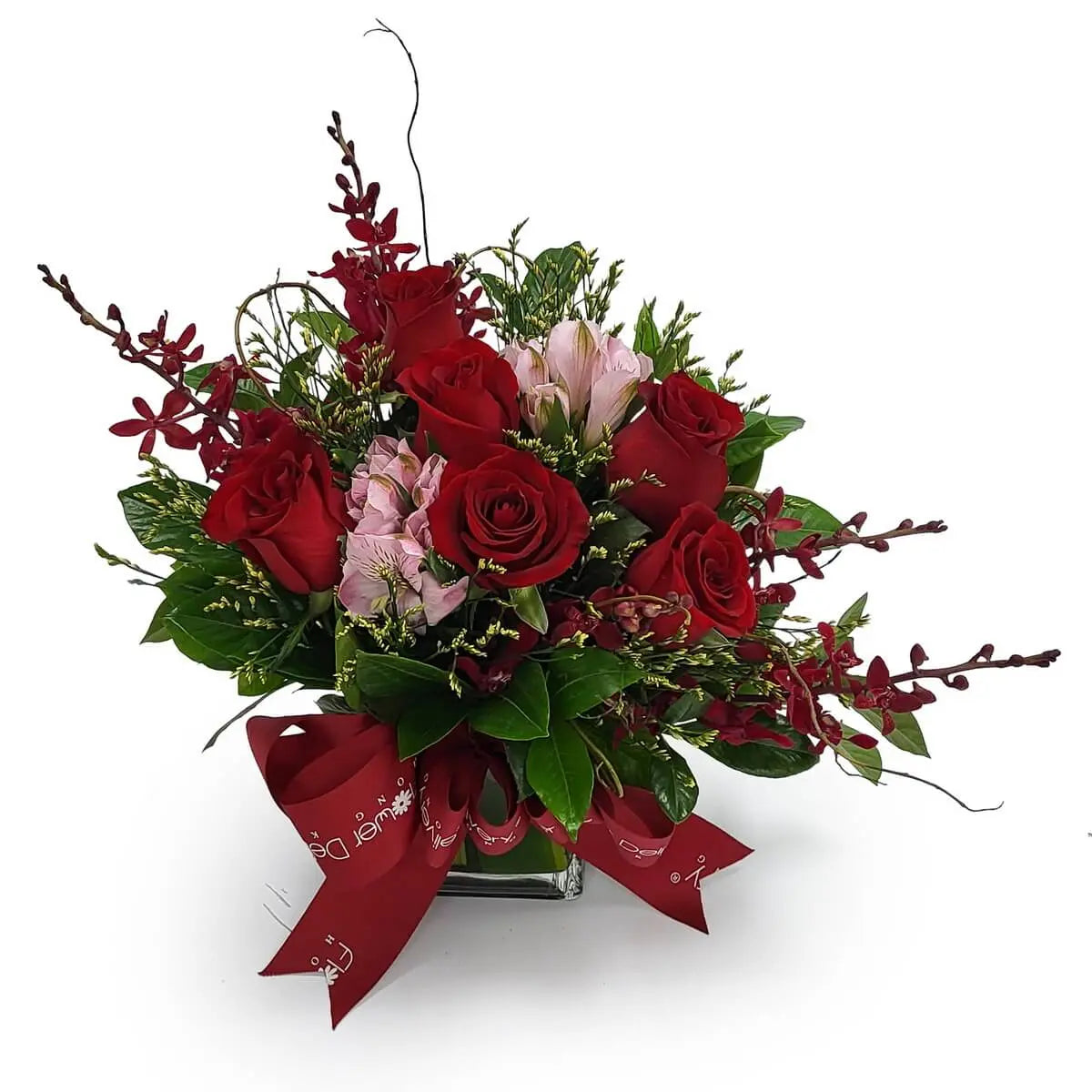 Square vase arrangement featuring red roses, pink alstroemeria, red orchids, and assorted foliage, tied with a bold red ribbon | 正方形玻璃瓶插紅玫瑰、粉紅百合及紅蘭花,搭配各式綠葉及紅絲帶裝飾。