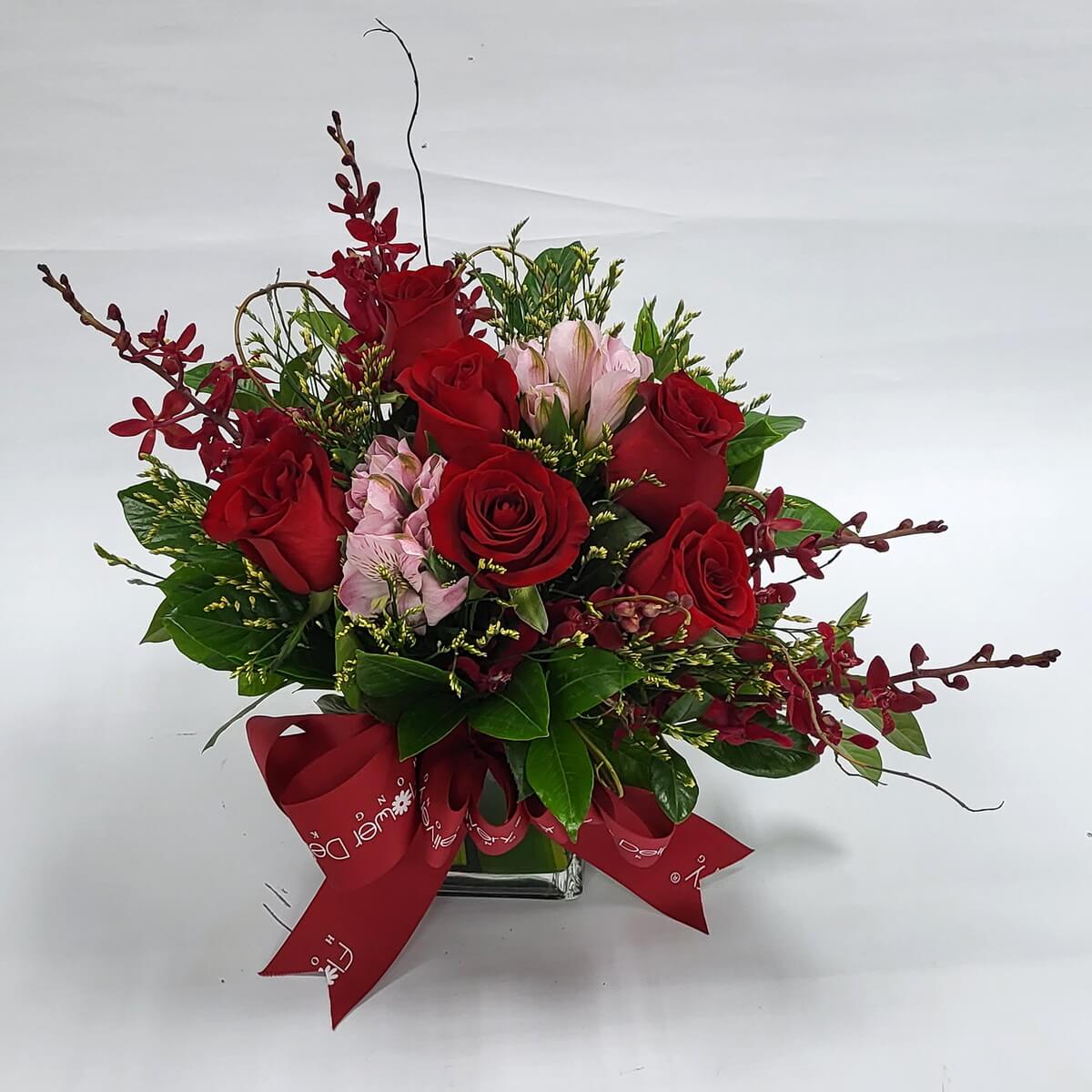 Romantic red and pink roses with orchids in a square vase, tied with a red ribbon 浪漫紅玫瑰配粉紅玫瑰及蘭花,插於方形玻璃瓶中,紅絲帶點綴,展現熱情與溫柔並存的魅力。