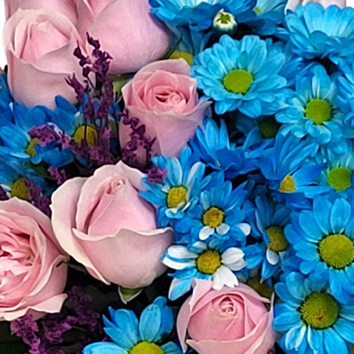 A joyful mix of soft pink roses, bright blue daisies, and purple statice flowers 柔美粉玫瑰與鮮亮藍色雛菊,佐以紫色勿忘我,展現歡樂與甜美的色彩組合。
