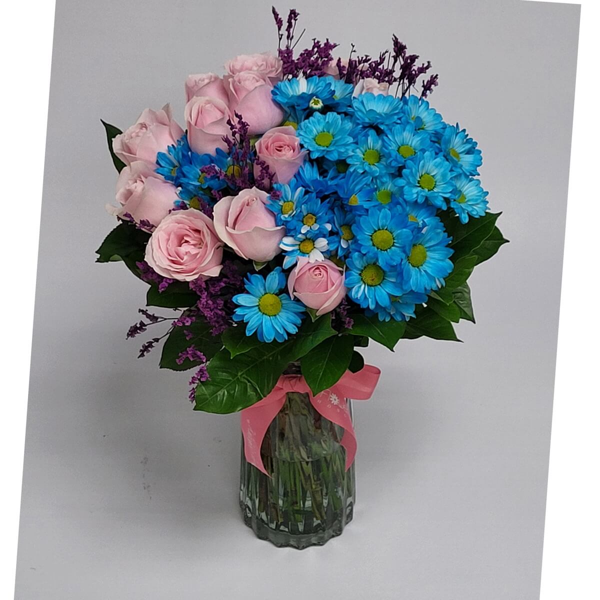 Charming bouquet with pink roses, vivid blue daisies & purple accents 粉玫瑰與藍色雛菊交織,點綴紫色配花,插於玻璃瓶中,粉紅絲帶增添甜美感。