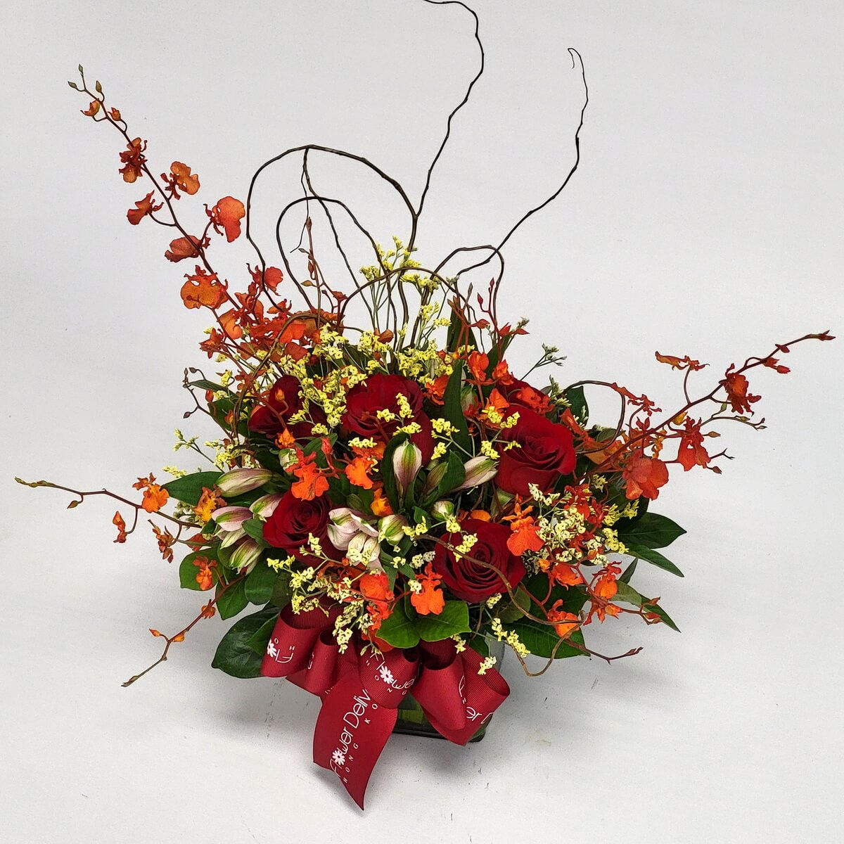 Compact arrangement featuring red roses, orange dancing orchids, pale alstroemeria, yellow statice, and curly branches 紅玫瑰、橙跳舞蘭、淡六出花、黃蠟菊與彎枝組合的整體花藝擺設