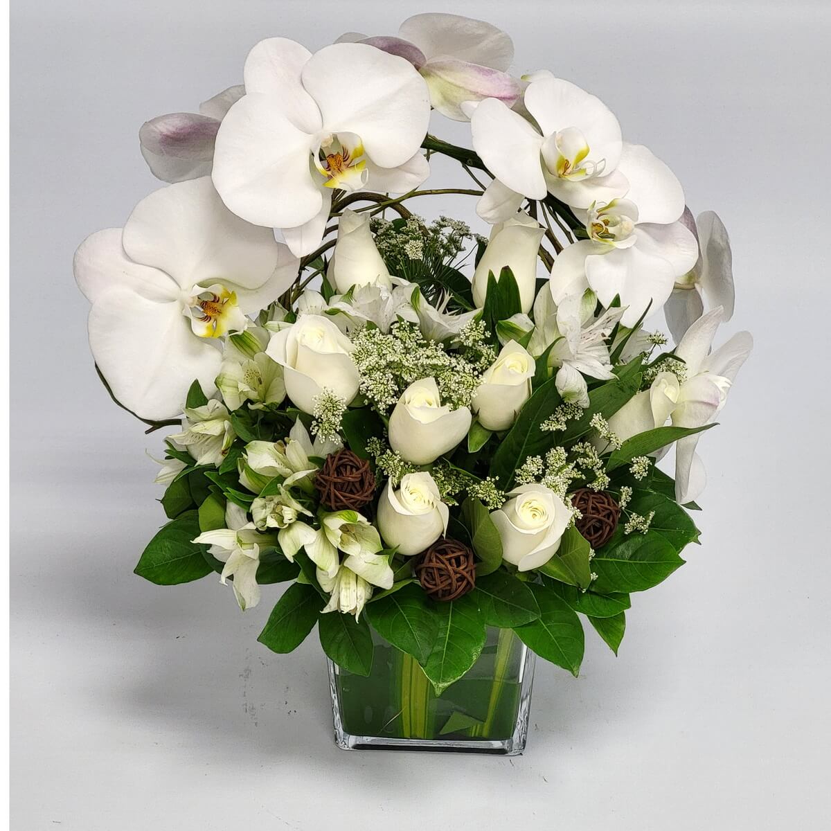 Elegant floral arrangement with white orchids, white roses, white alstroemeria, delicate filler flowers, rattan balls, and greenery in square glass vase 白蝴蝶蘭、白玫瑰、白六出花、精緻配花與藤球組合於方形玻璃瓶中