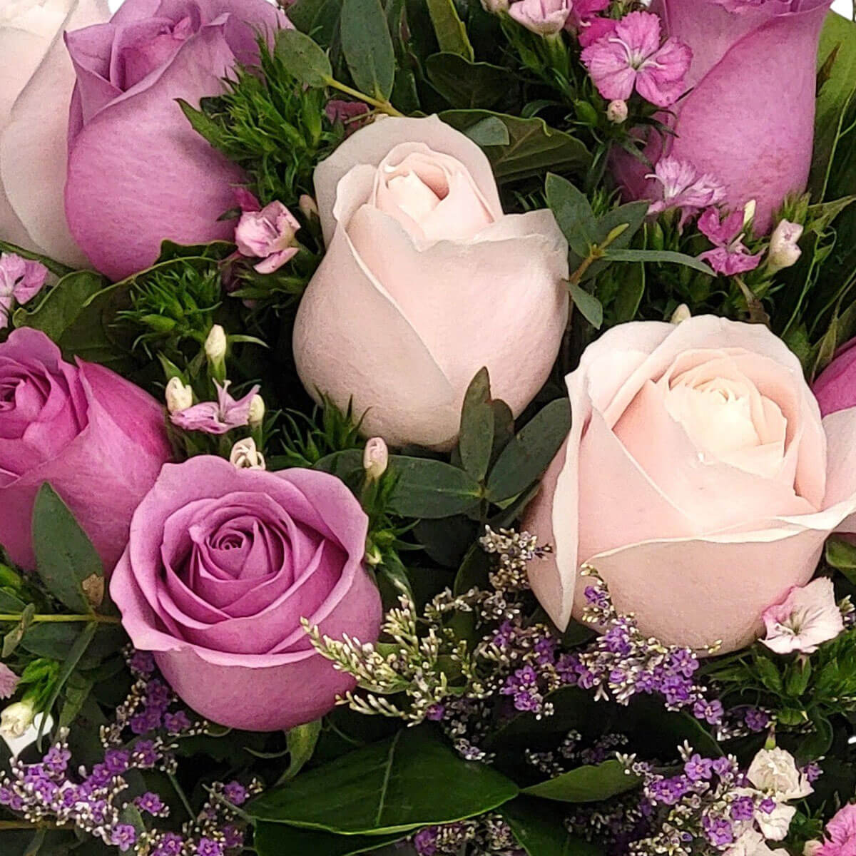 Soft pink and lavender roses nestled in greenery with accents of tiny violet blooms 柔粉與紫玫瑰交織,配以細緻紫花與綠意,婉約優雅,傳遞心中的細膩情感。