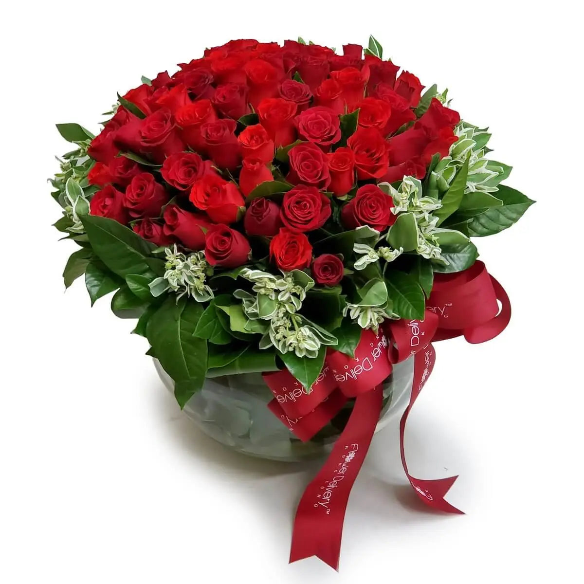 Lush round arrangement of red roses accented with mixed foliage in a clear bowl vase, tied with a red ribbon. | 豐盛紅玫瑰與各式綠葉組成的圓形花藝,插於透明缽型玻璃瓶中,綁有紅絲帶。