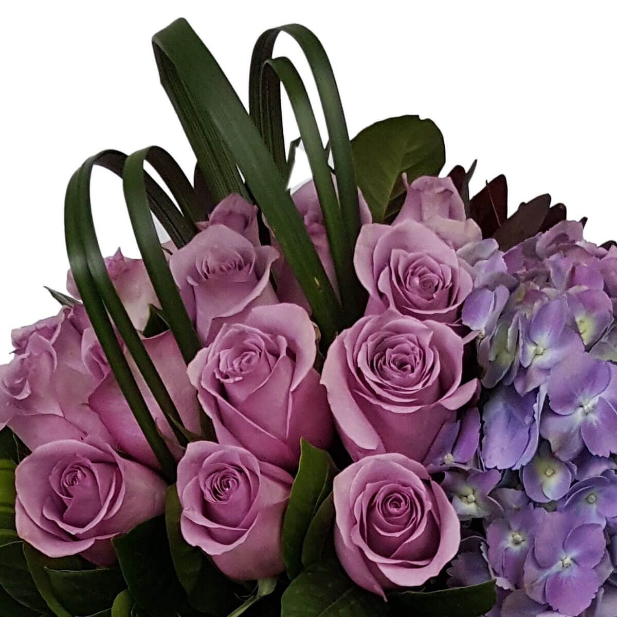 Detail view of a floral arrangement featuring lavender roses and clustered purple hydrangeas, accented with dark green foliage and looped grass blades - 薰衣草玫瑰與紫繡球花密集排列,配深綠葉與彎曲葉條點綴的花藝細節圖