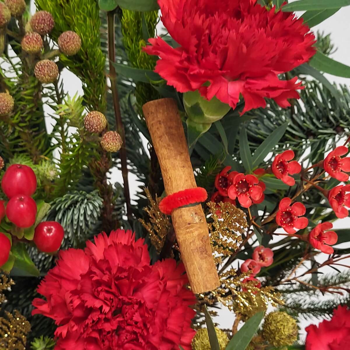 Close-up of red carnations, waxflowers, cinnamon stick, hypericum berries, pine, and golden accents - 紅康乃馨、蠟花、玉桂棒與松葉特寫