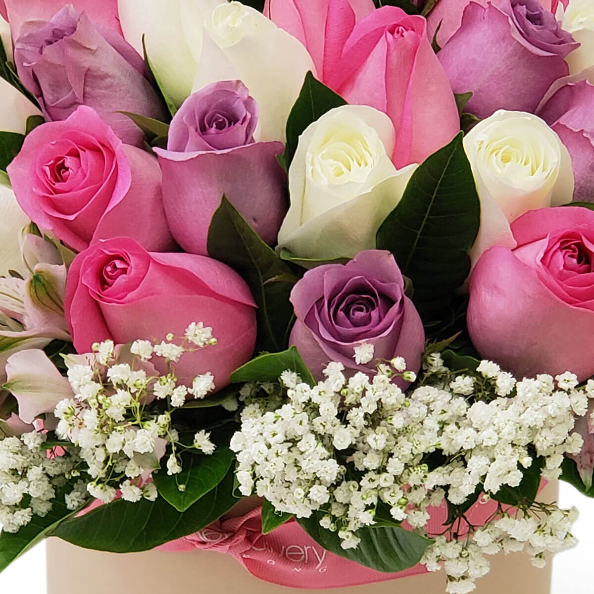 Detail view of a bouquet with pink, lavender, and white roses, accented by delicate baby's breath and dark green foliage in a soft-toned floral box - 粉紅、薰衣草與白玫瑰配白滿天星與深綠葉,柔色花盒設計的花束細節圖