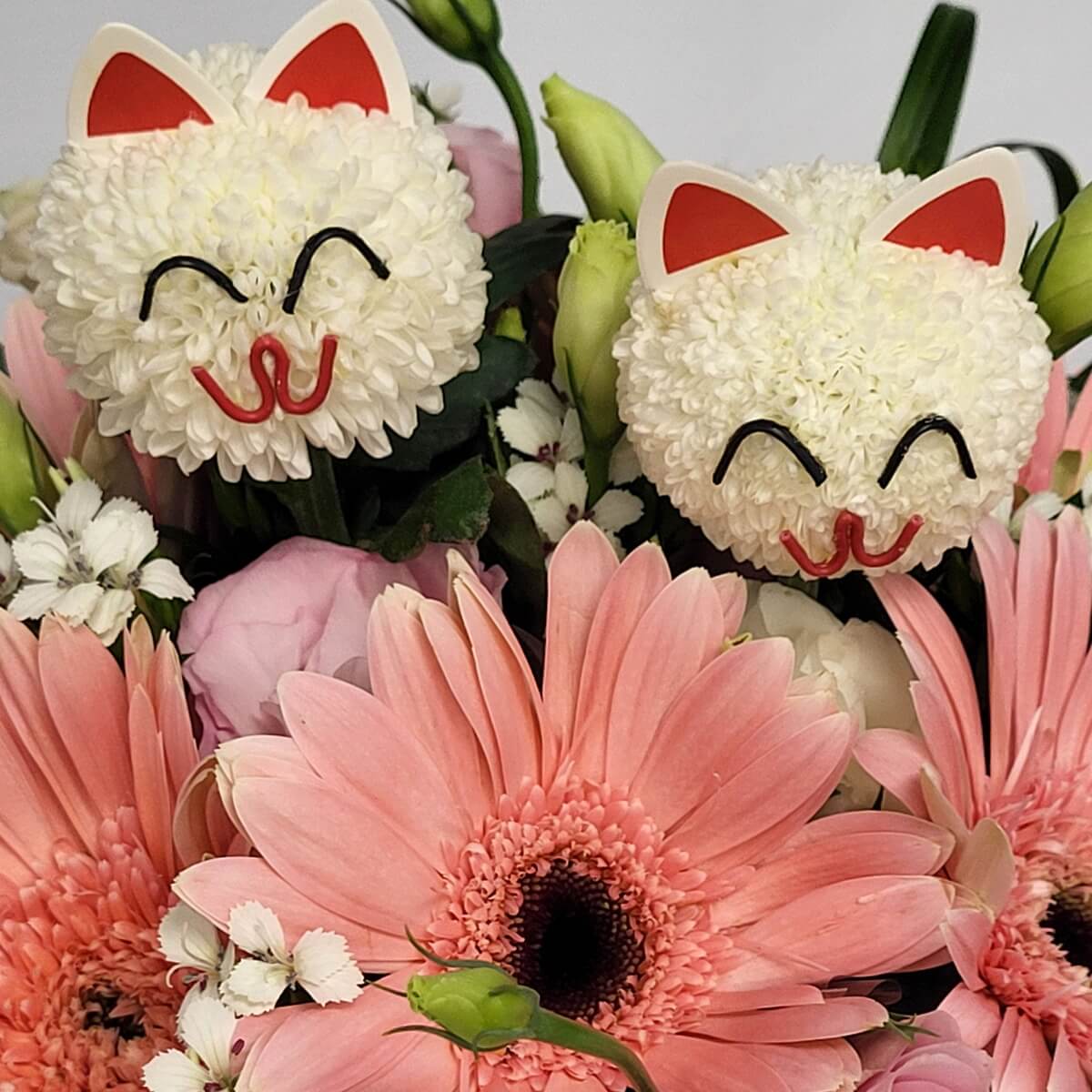 Full arrangement featuring white button chrysanthemums with cat faces, pink gerberas, lisianthus, dianthus, and green floral accents 仿貓臉白色乒乓菊與粉紅非洲菊、洋桔梗、白石竹及綠色花材組成的整體花束設計。