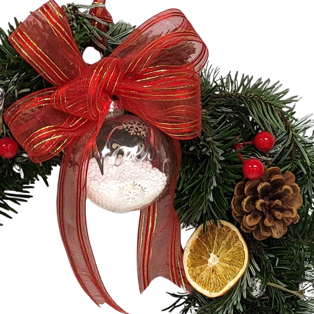 Festive wreath with pinecones, berries, and Noel ornament 節慶花圈上裝飾松針、松果、紅色漿果與乾燥橙片,中心懸掛透明「Noel」玻璃球,搭配紅金絲緞蝴蝶結,洋溢溫馨聖誕氛圍。
