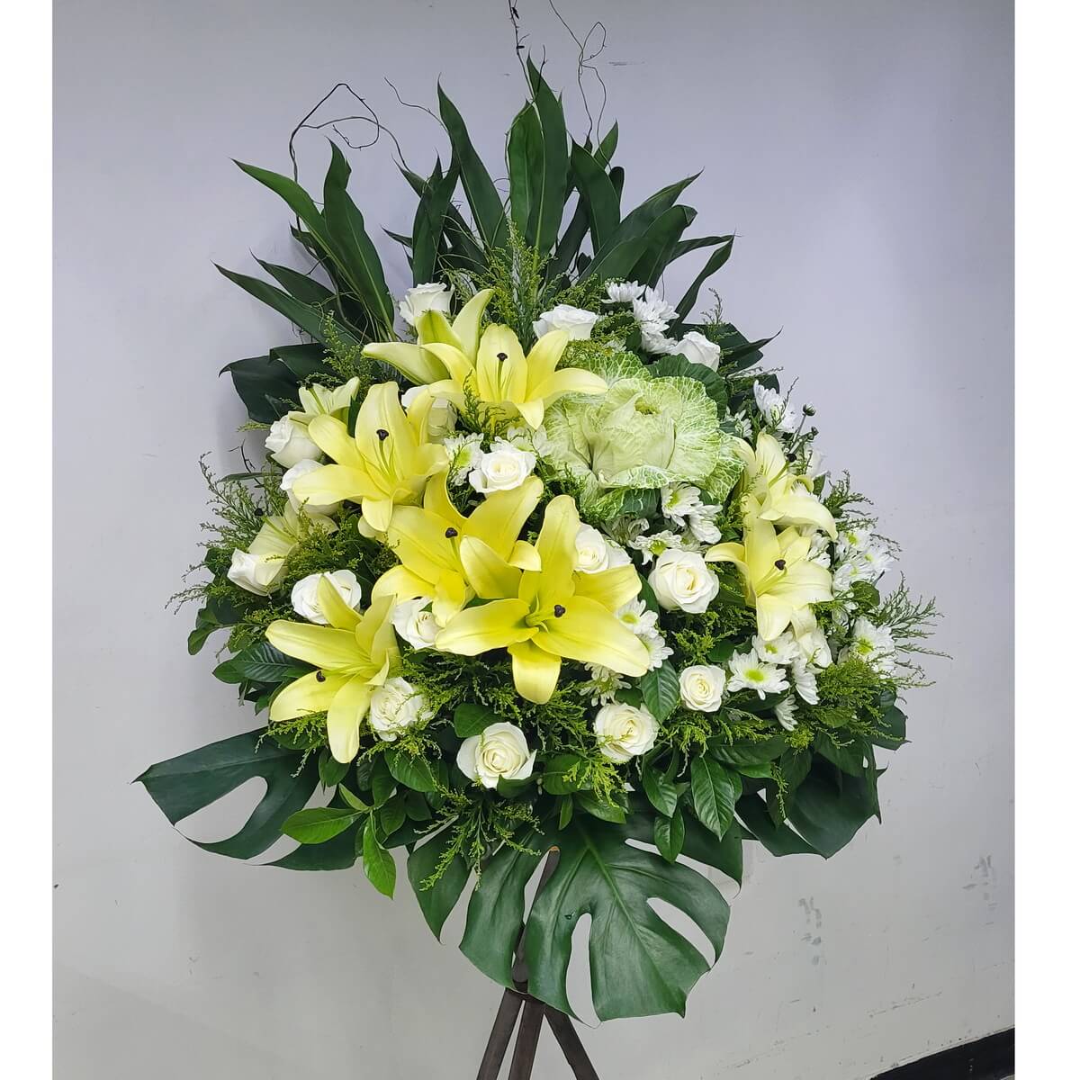 White condolence flower stand featuring roses, chrysanthemums, eustomas, hydrangeas, and yellow-centered daisies. 白玫瑰、菊花、桔梗、繡球花配小雛菊,構成素雅悼念花牌。