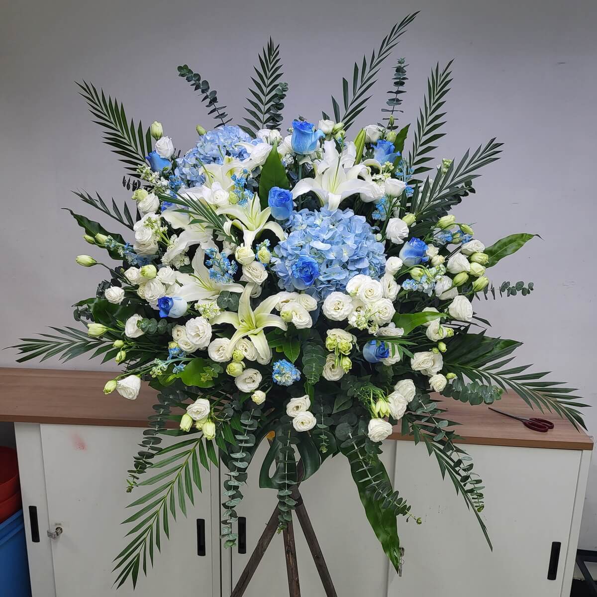 A dignified condolence arrangement of soft blue roses, hydrangeas, white lilies, and eustomas — a heartfelt tribute.
溫柔藍玫瑰、繡球花與白百合、桔梗交織成莊重悼念花牌,寄予最深追思。