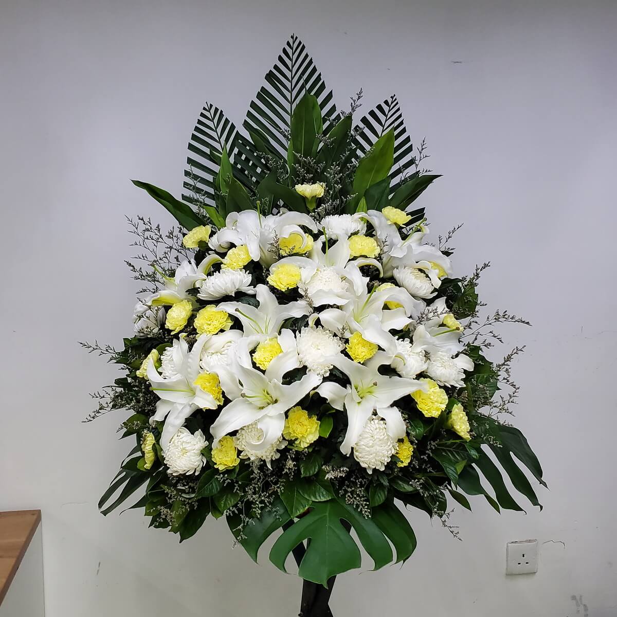 Sympathy stand featuring white lilies, chrysanthemums, and yellow carnations, expressing deep condolences.
白百合、白菊與黃康乃馨悼念花牌,寄託無限哀思與敬意。