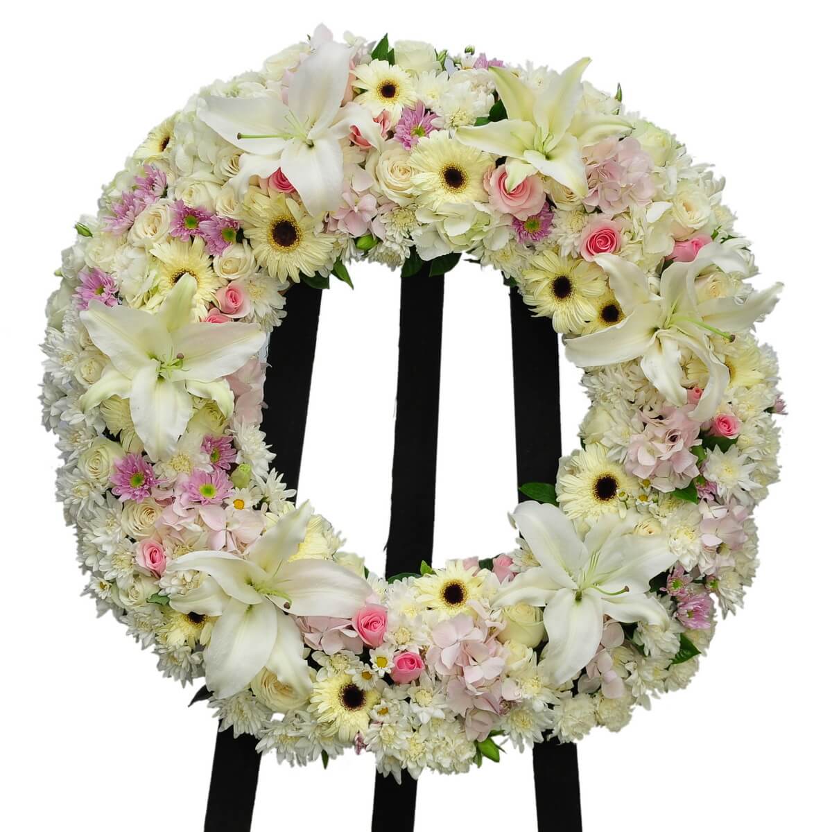 Round floral wreath featuring white lilies, ivory gerberas, pink roses, pink hydrangeas, and white chrysanthemums. 圓形花圈以白百合、奶油太陽菊、粉紅玫瑰、粉紅繡球及白菊花編製而成,設於黑色支架上。