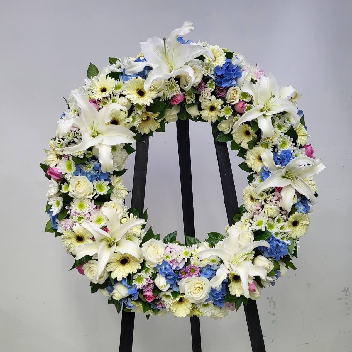 Condolence wreath adorned with white lilies, cream gerberas, pink roses, and hydrangeas — offering a tender farewell.
悼念花圈以百合、非洲菊、粉玫瑰與繡球花點綴,傳遞溫柔告別之意。