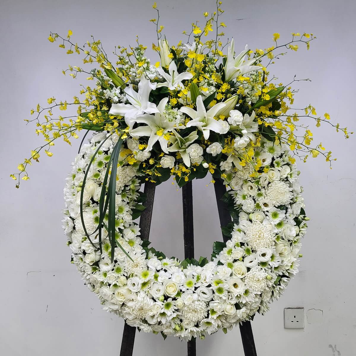 Standing wreath with white lilies, yellow dancing orchids, white roses, button chrysanthemums, and lisianthus 白百合、黃跳舞蘭、白玫瑰、乒乓菊與洋桔梗立式花圈