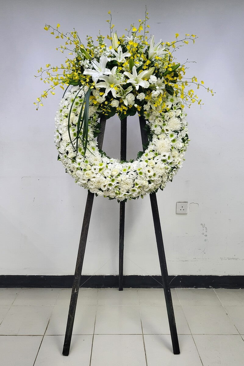 Indoor standing wreath featuring white oriental lilies, yellow dancing orchids, white roses, button chrysanthemums, lisianthus, and carnations 室內立式花圈設計,配白色東方百合、黃色跳舞蘭、白玫瑰、乒乓菊、洋桔梗及康乃馨
