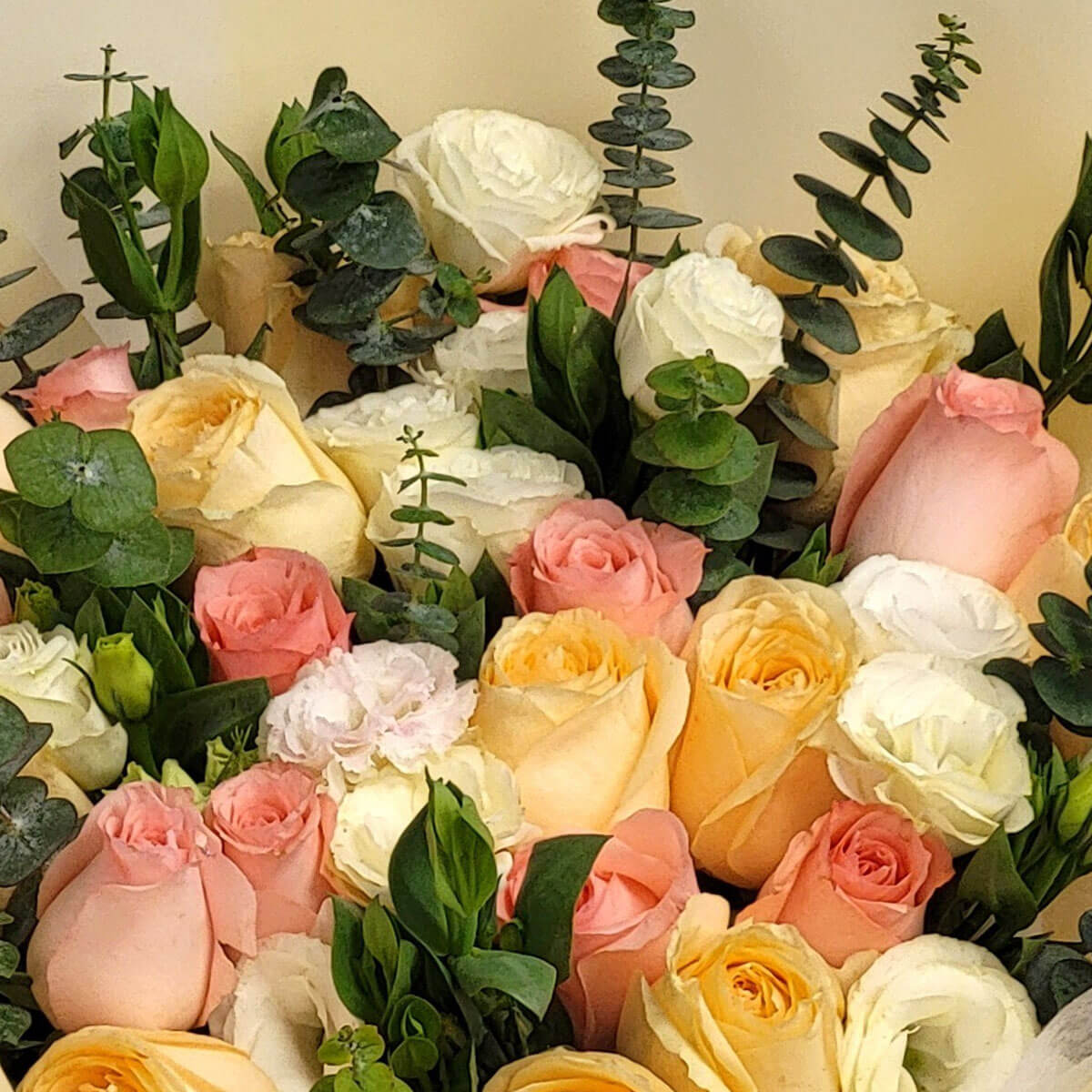 An elegant bouquet of pastel roses in peach, blush, and white with eucalyptus accents 夢幻花束由粉橘、嫩粉與奶白玫瑰組成,點綴尤加利葉,清新而柔美。