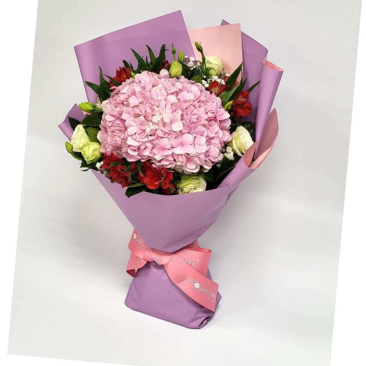 Hand-tied bouquet featuring pink hydrangea, red alstroemeria, and lisianthus wrapped in lilac paper 粉紅繡球花為主,搭配紅色百合草及淡綠洋桔梗,紫粉色包裝紙手綁設計,花材飽滿。