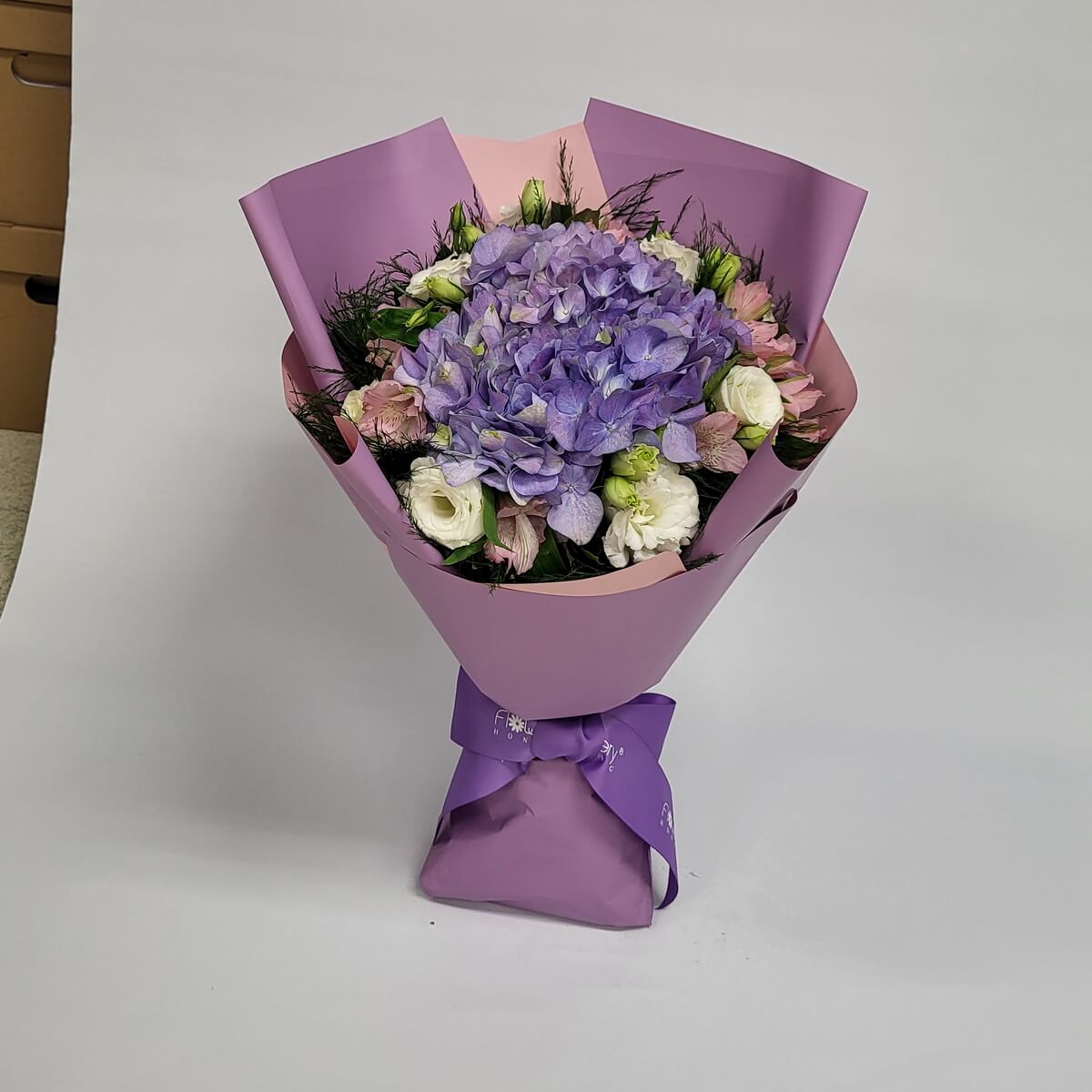 Elegant bouquet with a central purple hydrangea, framed by white eustoma and blush alstroemeria, wrapped in lavender and pink – 中央紫繡球花,襯以白桔梗與粉六出花,紫粉色包裝,典雅大方