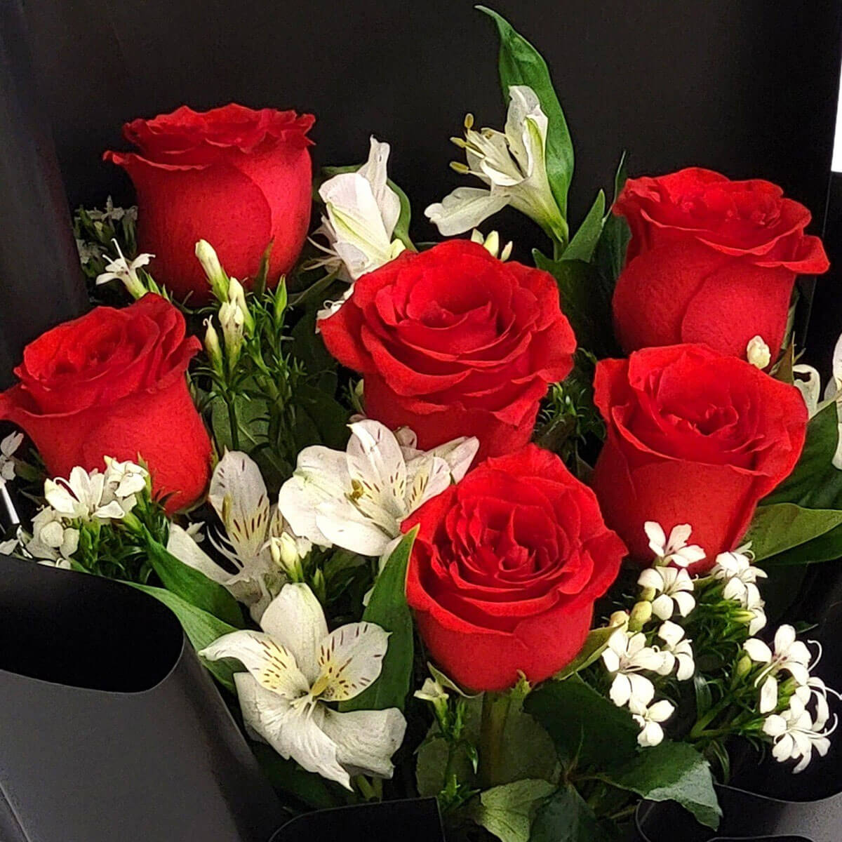 A romantic bouquet of red roses and white lilies, elegantly wrapped in black 紅玫瑰配白百合,黑色包裝襯托出花束的經典與優雅,象徵純潔與熱情的交融。